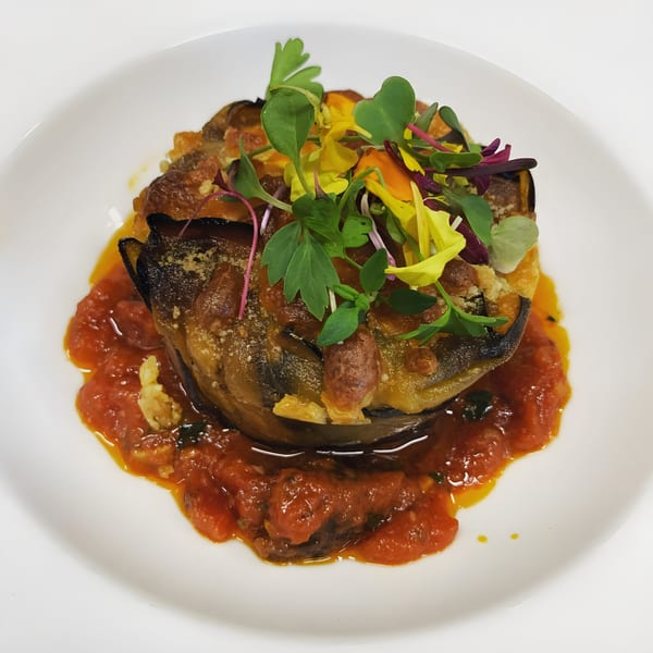 Tre Monti's eggplant parmesan with tomato sauce, garnished with microgreens and edible flowers.