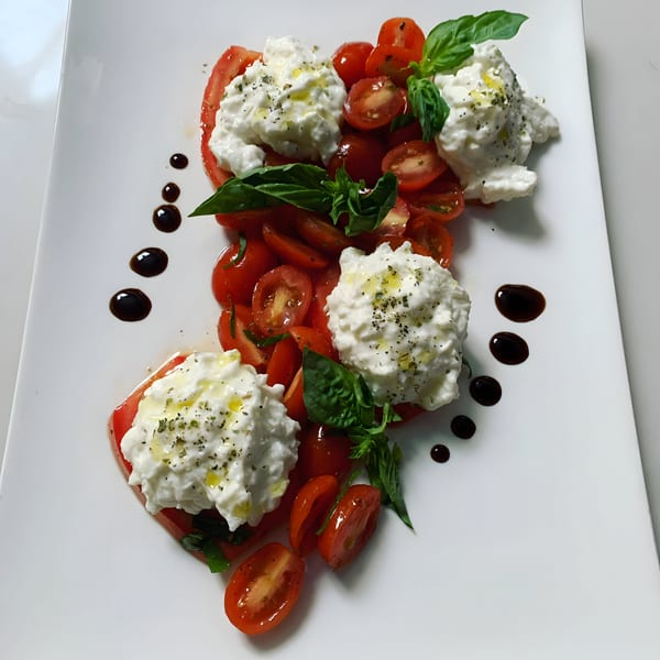 Italian Caprese salad with fresh tomatoes, creamy mozzarella, basil, olive oil, and balsamic glaze.
