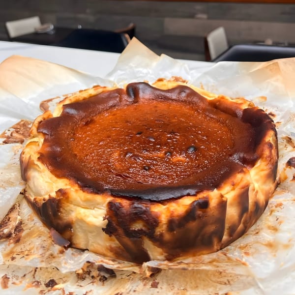 A freshly baked, golden-brown Basque cheesecake with a caramelized top, resting on parchment paper.