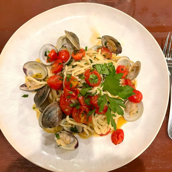 Tre Monti's linguine alle vongole with fresh clams, cherry tomatoes, and parsley on a white plate.