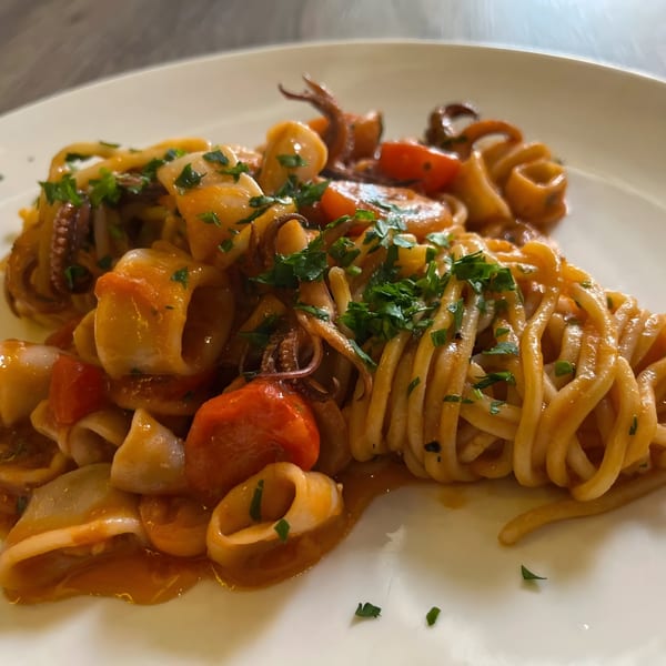 Italian pasta with calamari, cherry tomatoes, and parsley in a rich red sauce.